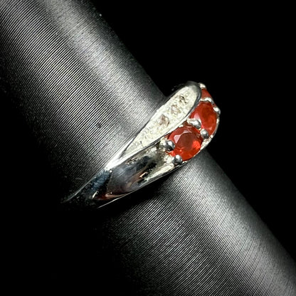Side view of silver Mexican fire opal and diamond ring against a black background.  The ring's shank is in focus.