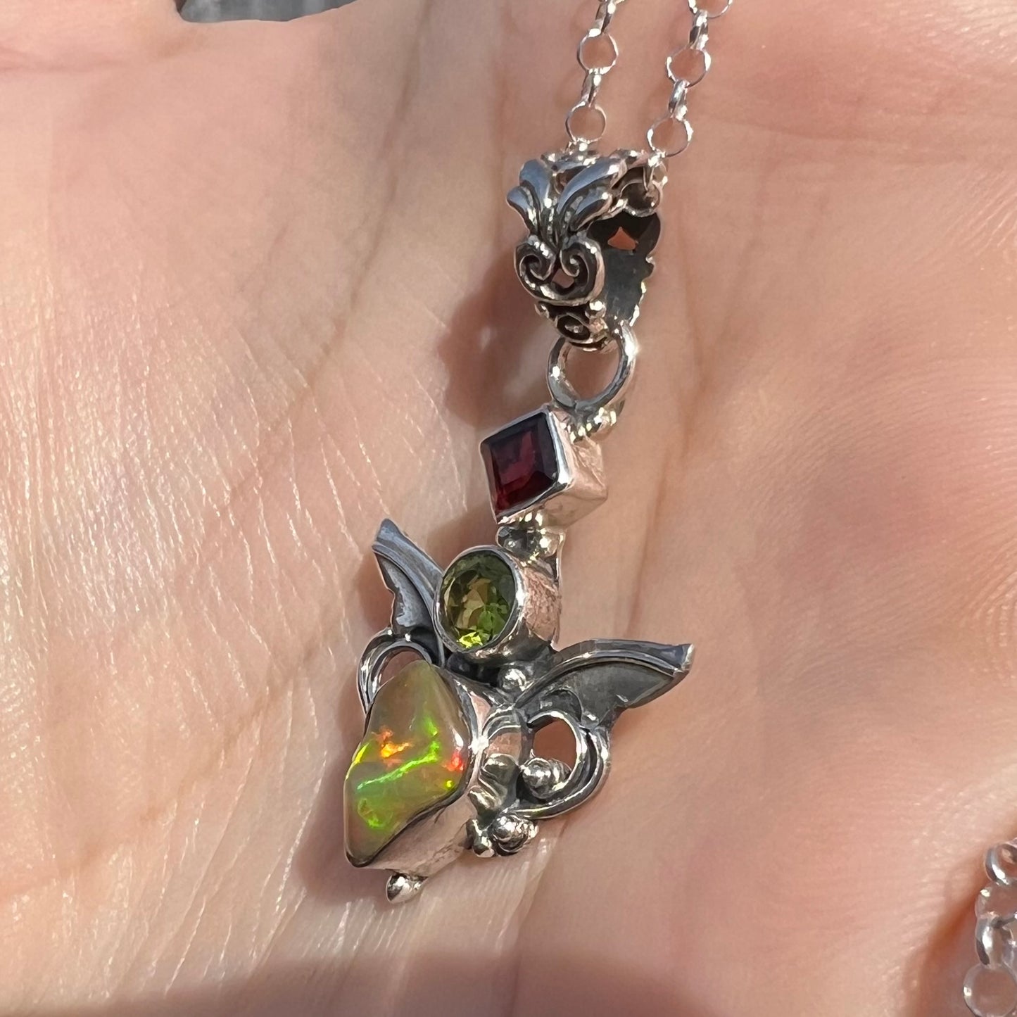 A sterling silver angel pendant set with an Ethiopian fire opal, peridot, and garnet.
