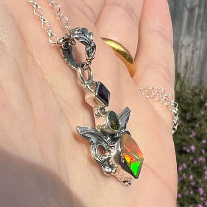 A sterling silver angel pendant set with an Ethiopian fire opal, peridot, and garnet.