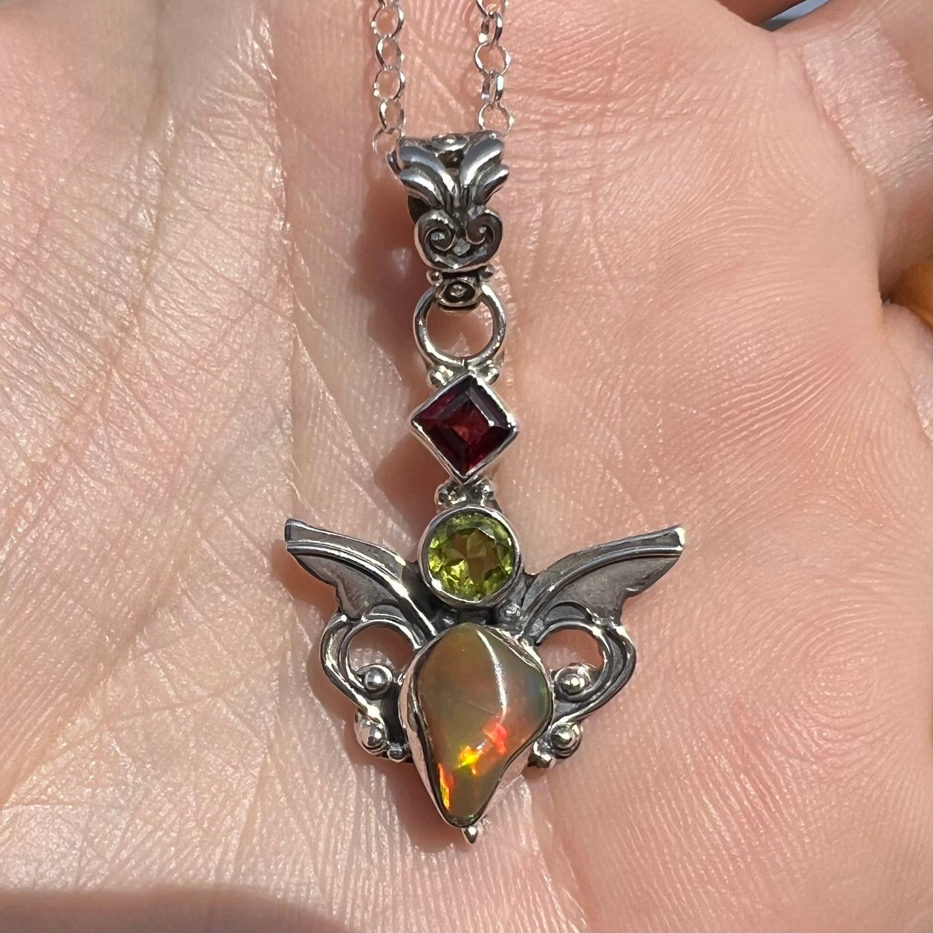 A sterling silver angel pendant set with an Ethiopian fire opal, peridot, and garnet.