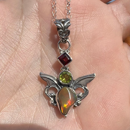 A sterling silver angel pendant set with an Ethiopian fire opal, peridot, and garnet.