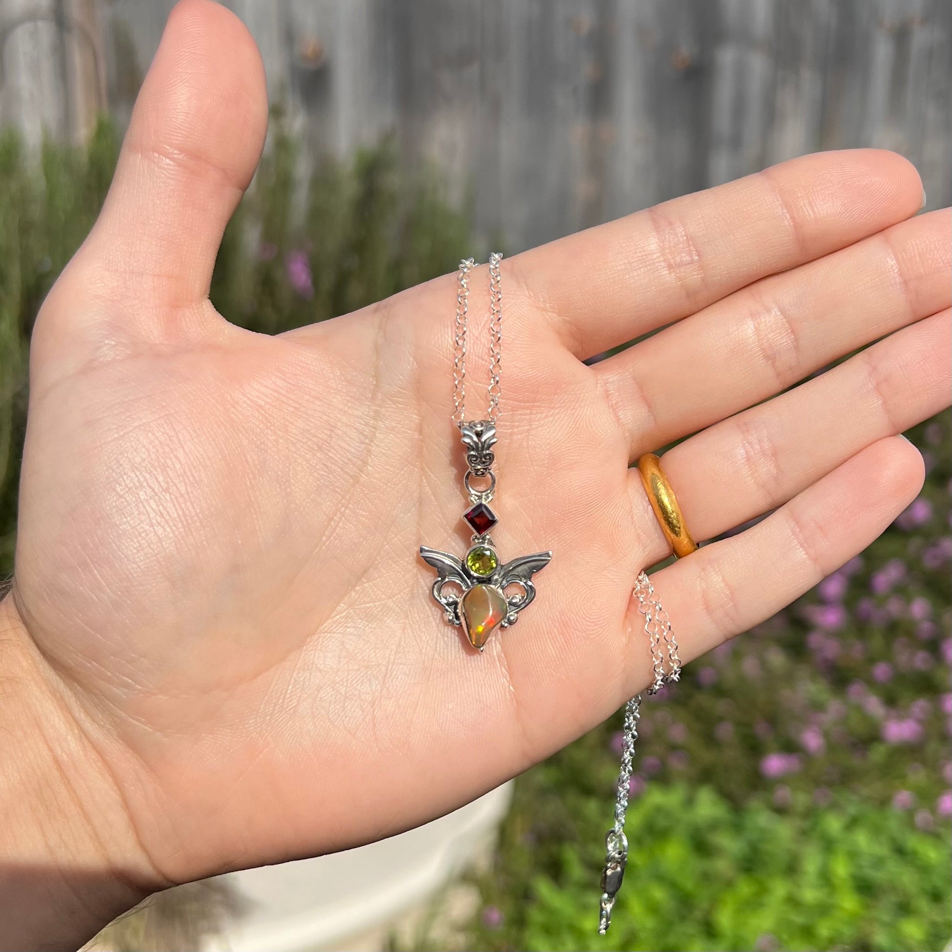 A sterling silver angel pendant set with an Ethiopian fire opal, peridot, and garnet.