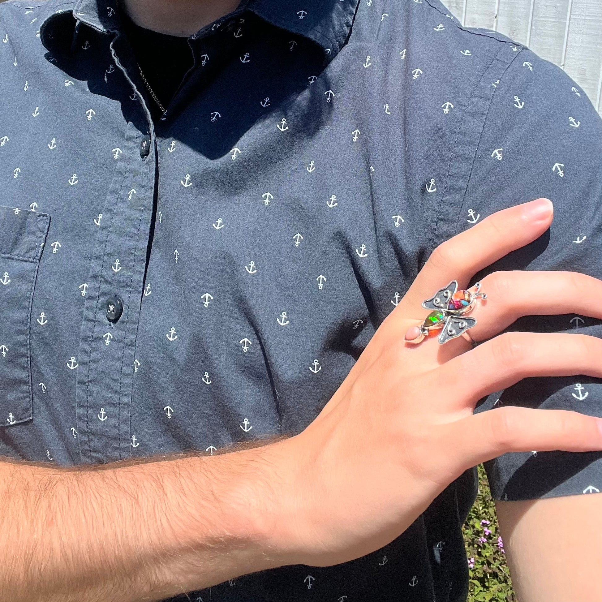 A silver opal butterfly ring worn on a hand as it rests on the model's opposing shoulder.