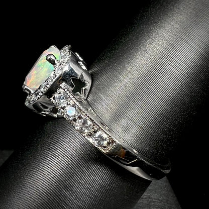 Side view of silver opal and cubic zirconia ring, viewing the ring from its shank; the ring has star shaped cutouts visible from beneth its gallery