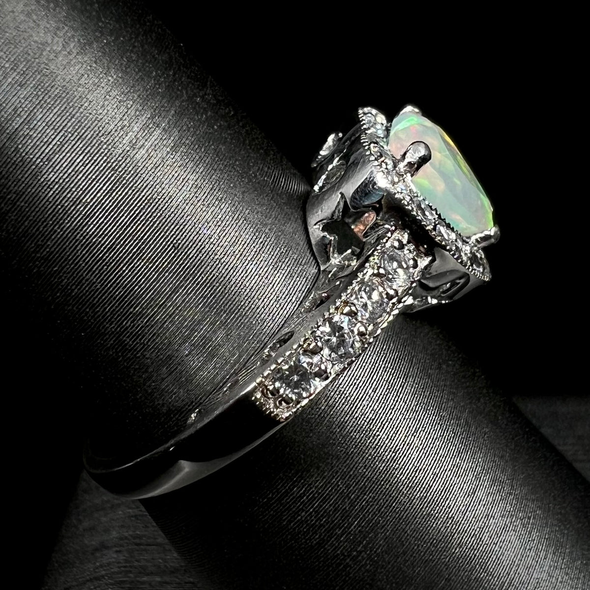 Side view of silver opal and pave set CZ ring on ring display, focusing on ring's shank and star-shaped cutout beneath ring's gallery