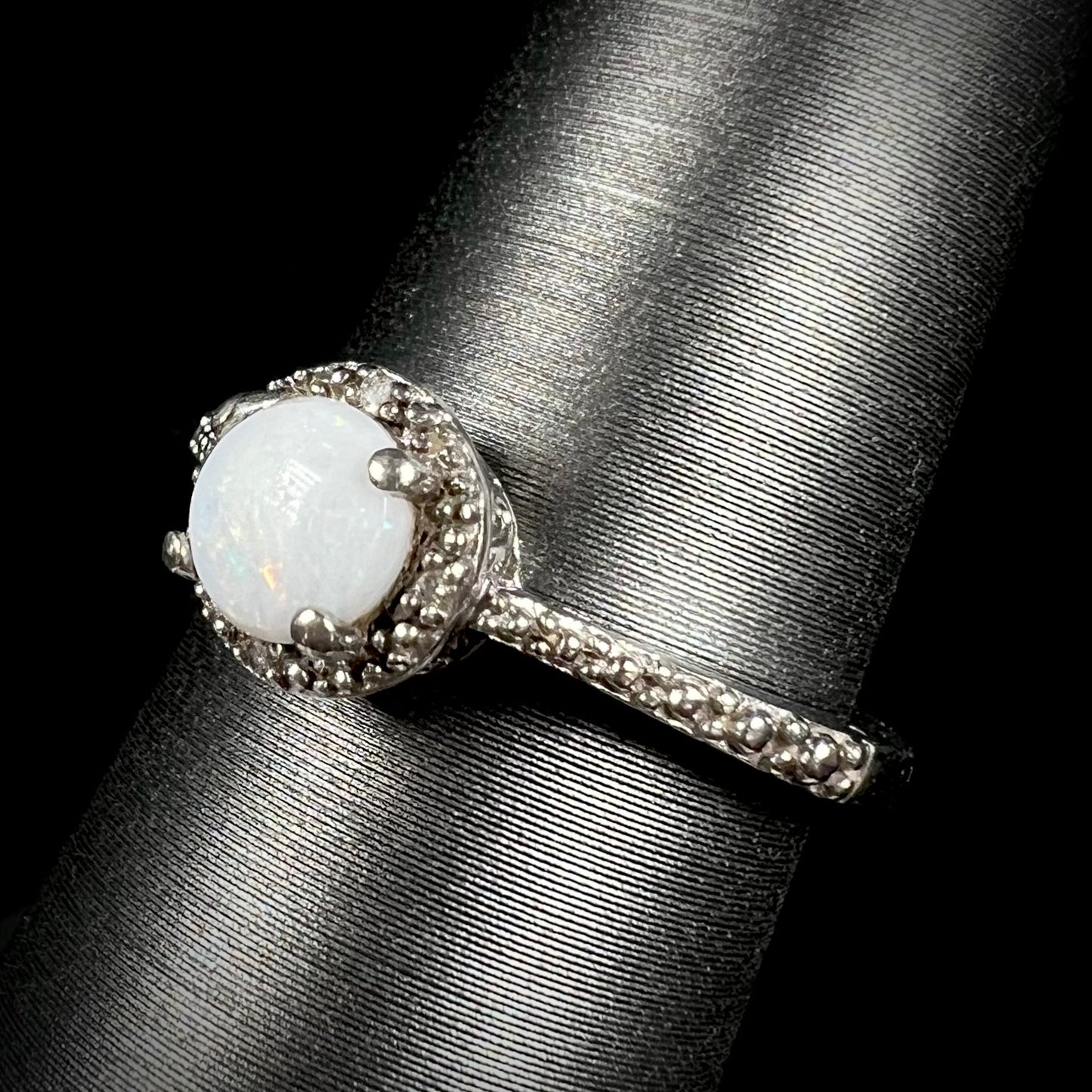 Angled view of a sterling silver white opal and diamond ring with a halo design.
