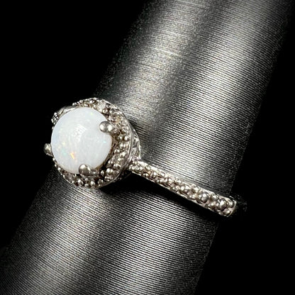 Angled view of a sterling silver white opal and diamond ring with a halo design.