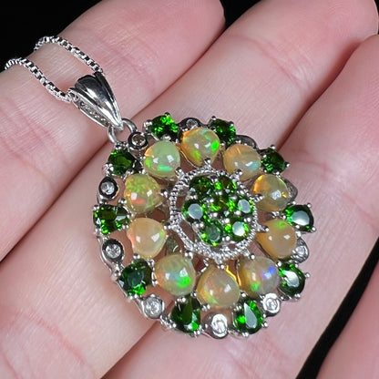 A silver Ethiopian opal and chrome diopside pendant held at an angle.