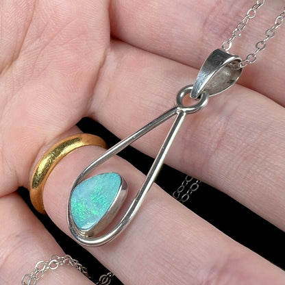Sterling silver opal doublet necklace shown close-up in a hand from an angled view.