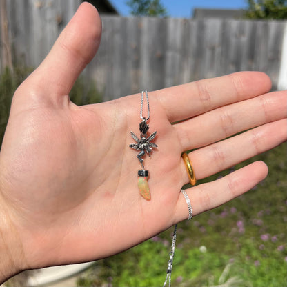 A sterling silver fairy necklace with an Ethiopian fire opal crystal, shown in a hand outside in sunlight.