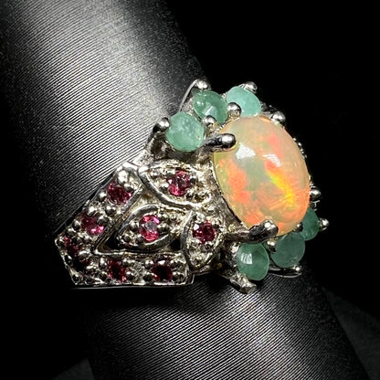 Angled close-up of sterling silver opal, garnet, and emerald ring on ring display