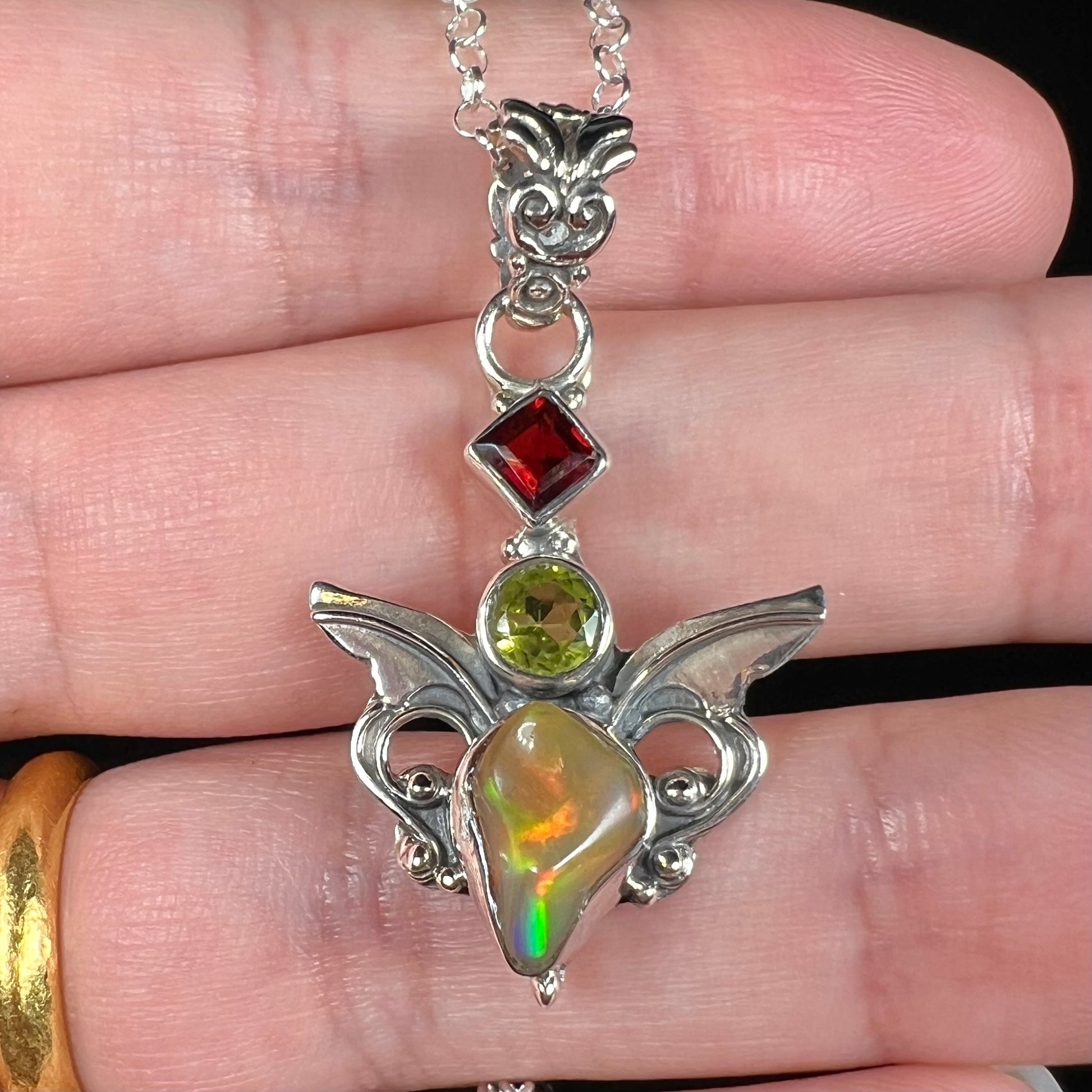 A sterling silver angel pendant set with an Ethiopian fire opal, peridot, and garnet.