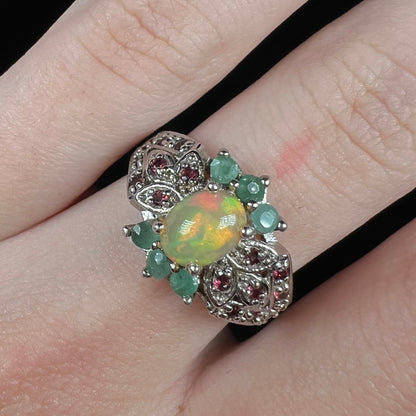 Close-up of sterling silver Ethiopian fire opal ring with green beryl and garnet accents, worn on finger