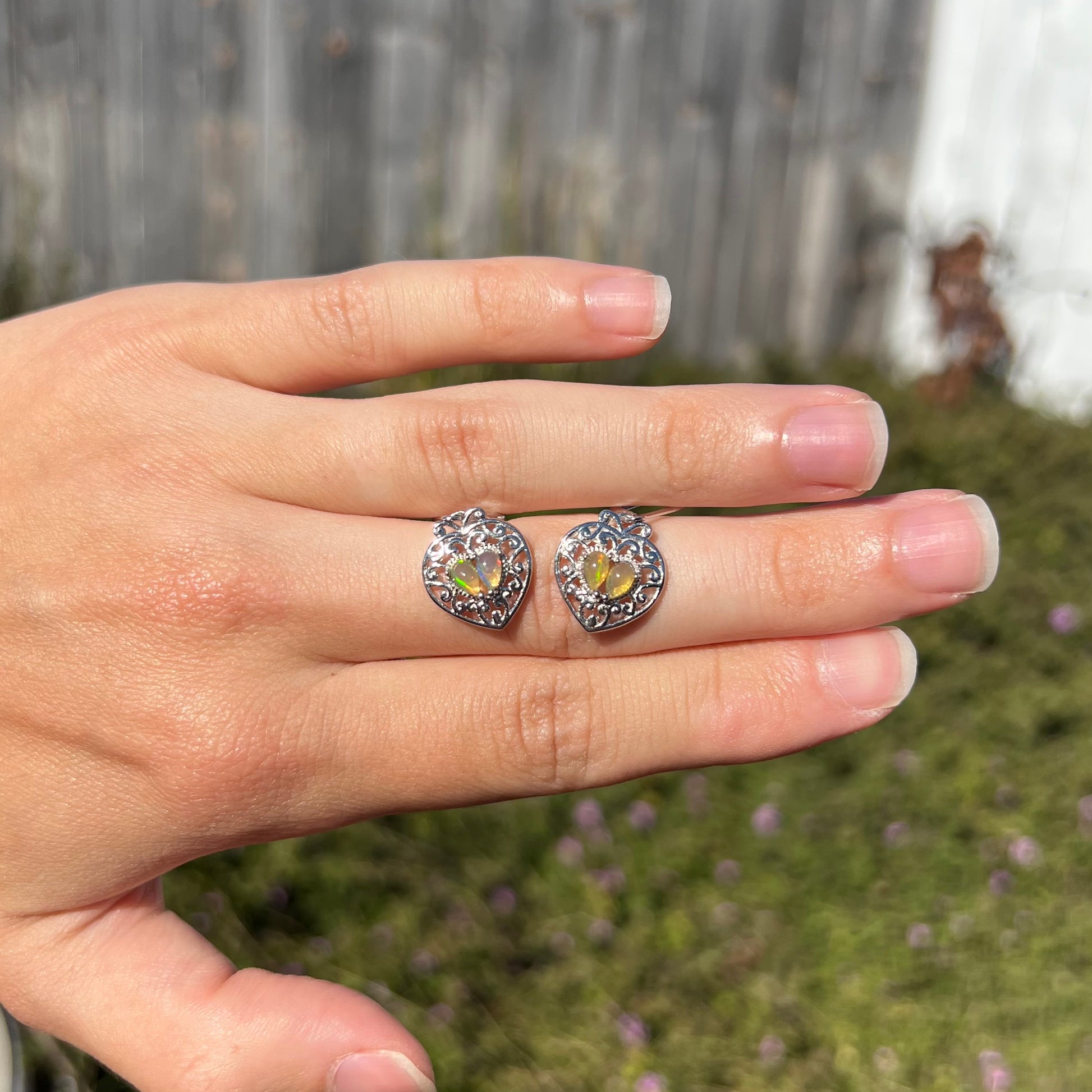 A pair of dangling sterling silver filigree heart earrings, each set with two Ethiopian opals.