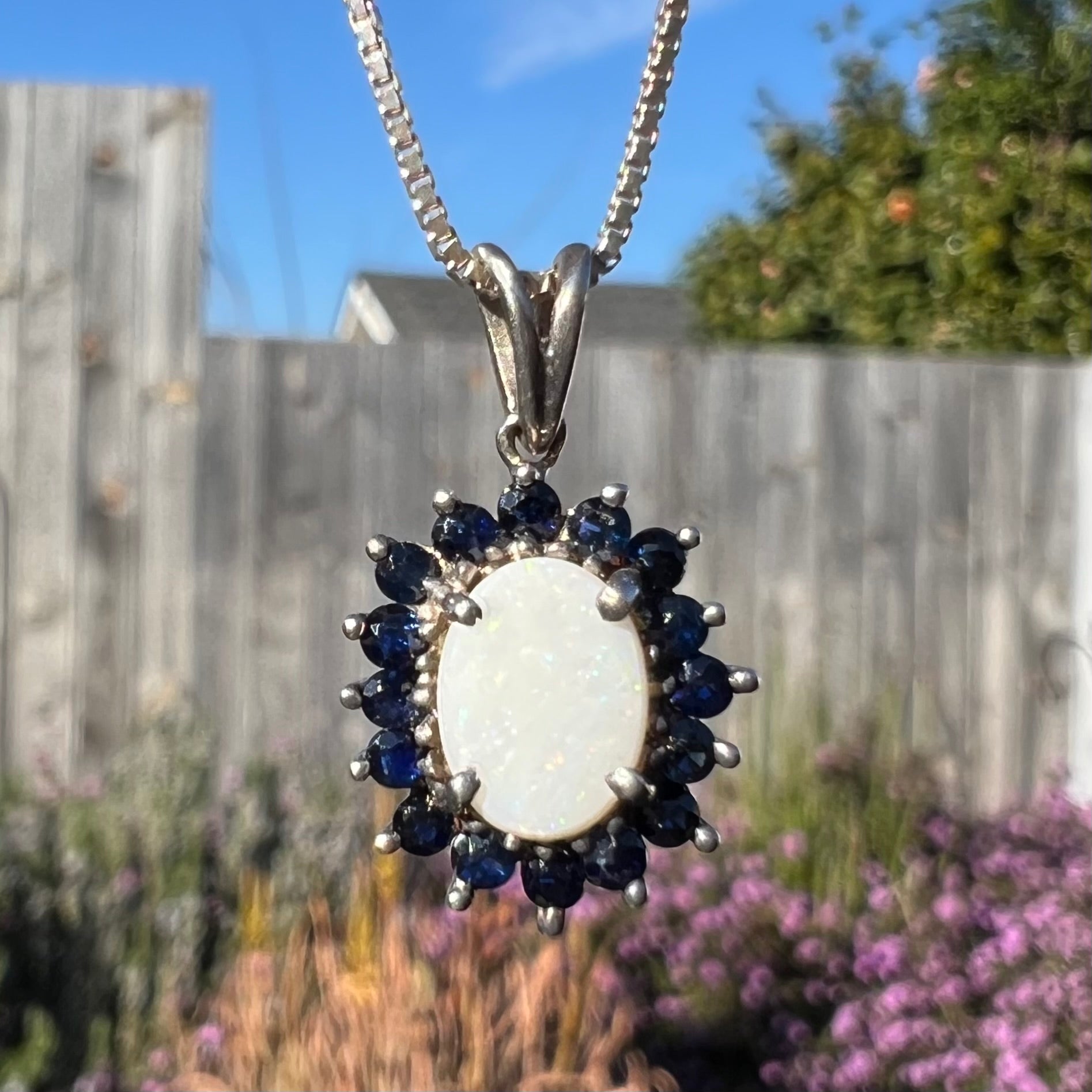 A macro close-up of a silver opal necklace in natural light, showing tiny white pinfire specks.