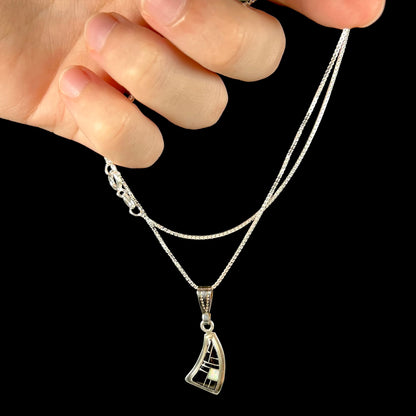 Hand holding silver opal and onyx necklace by its chain against a black background.