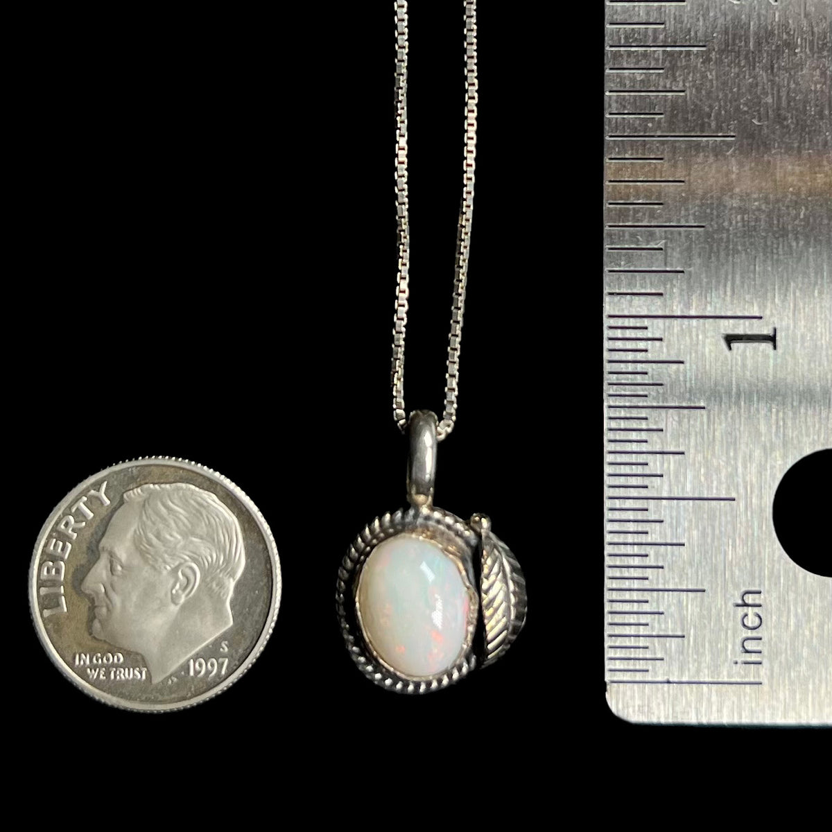 Sterling silver Southwest-style opal pendant measuring 0.8 inch long shown between US dime coin and ruler for scale
