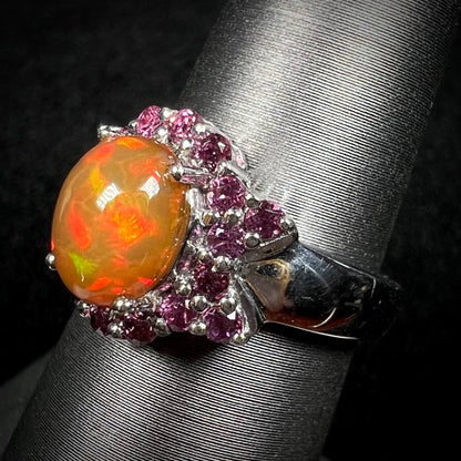 Close-up angled view of sterling silver Ethiopian fire opal and rhodolite garnet ring on display.  Opal has red flashes of color
