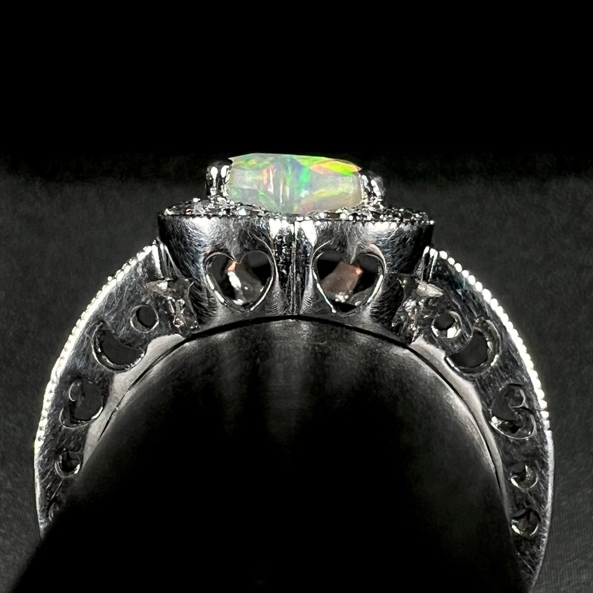 Side gallery profile view of women's sterling silver opal ring; open heart and crecent moon-shaped cutouts are visible along the ring's gallery and shank