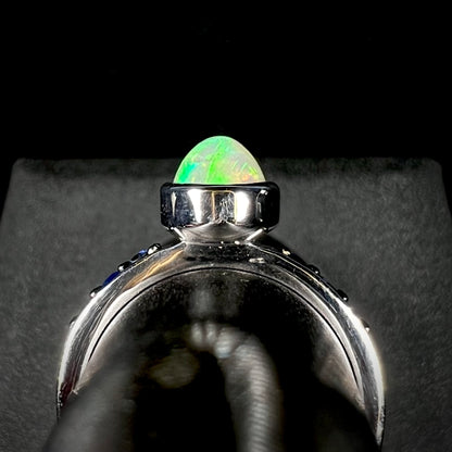 Gallery side angle of silver Ethiopian opal ring against black and gray background.  The silver bezel is in view.