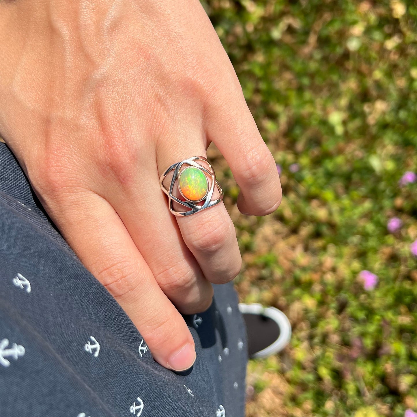 A hand resting on a hip while wearing a silver Ethiopian opal ring in the sunlight.