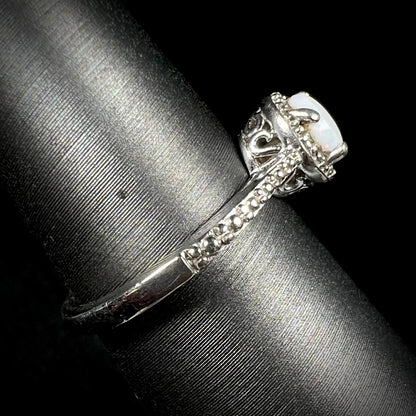 The side shank and filigree design of a sterling silver white opal and diamond ring with a halo design.