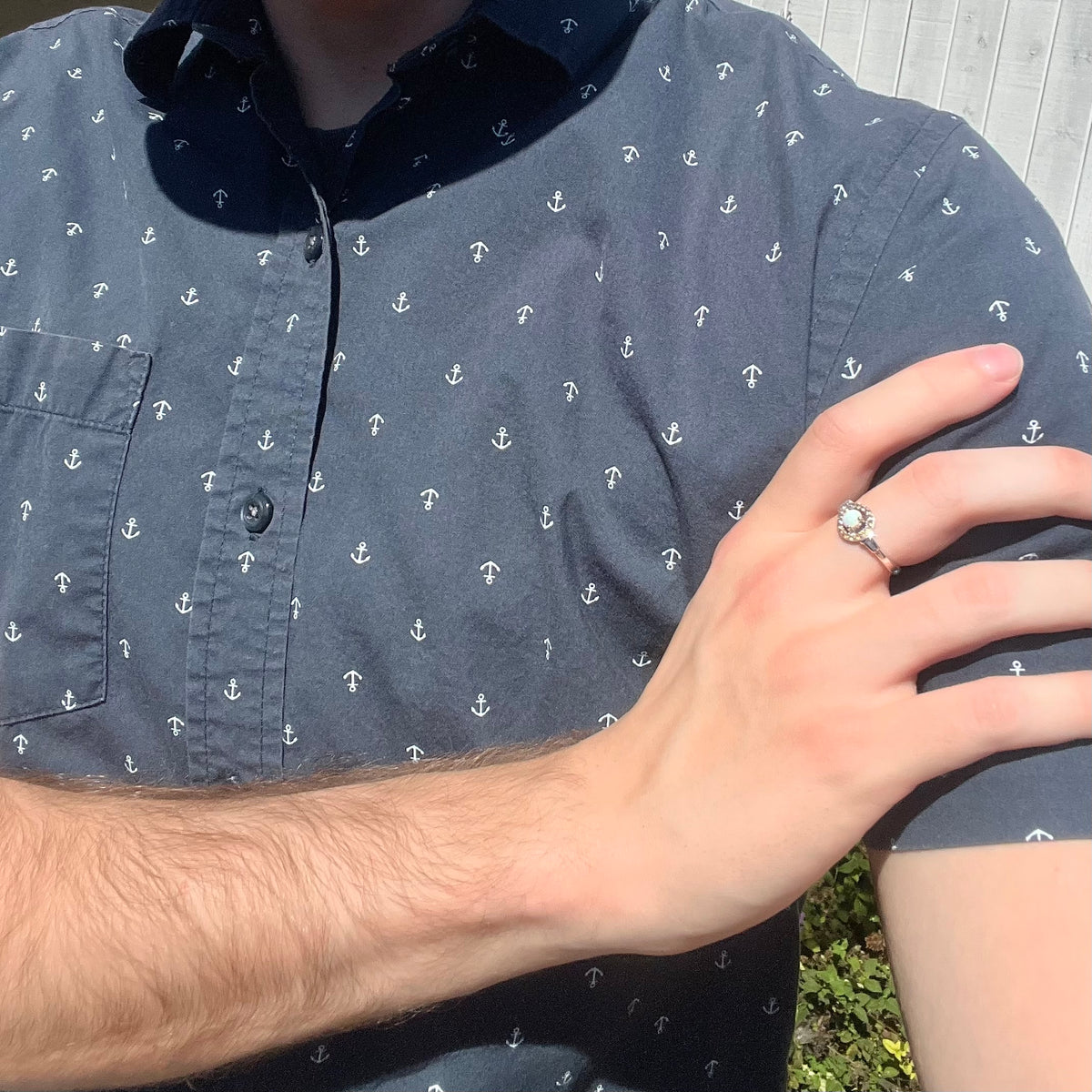 Close-up of person resting hand on opposing shoulder in sunlight wearing women's sterling silver opal and smoky quartz ring
