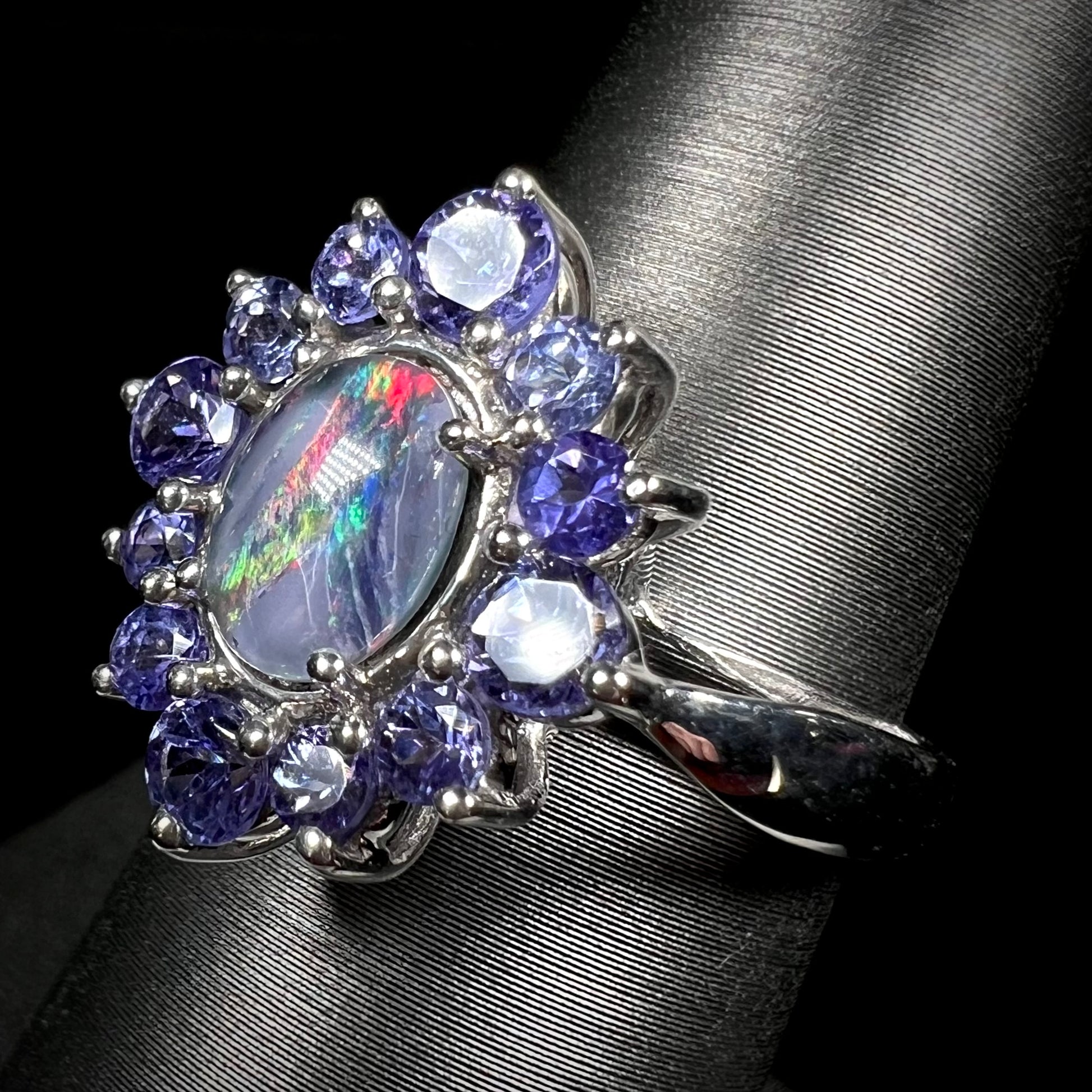 A silver opal triplet ring mounted with a halo of tanzanites.