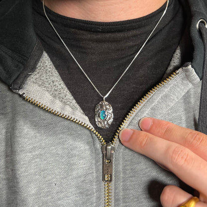 A unisex sterling silver pinecone-inspired opal triplet necklace worn around a neck on a dark shirt.