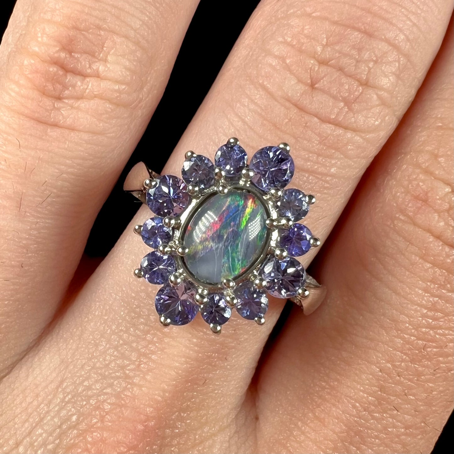 A sterling silver floating-style ring mounted with a black opal triplet in a halo of tanzanite stones.