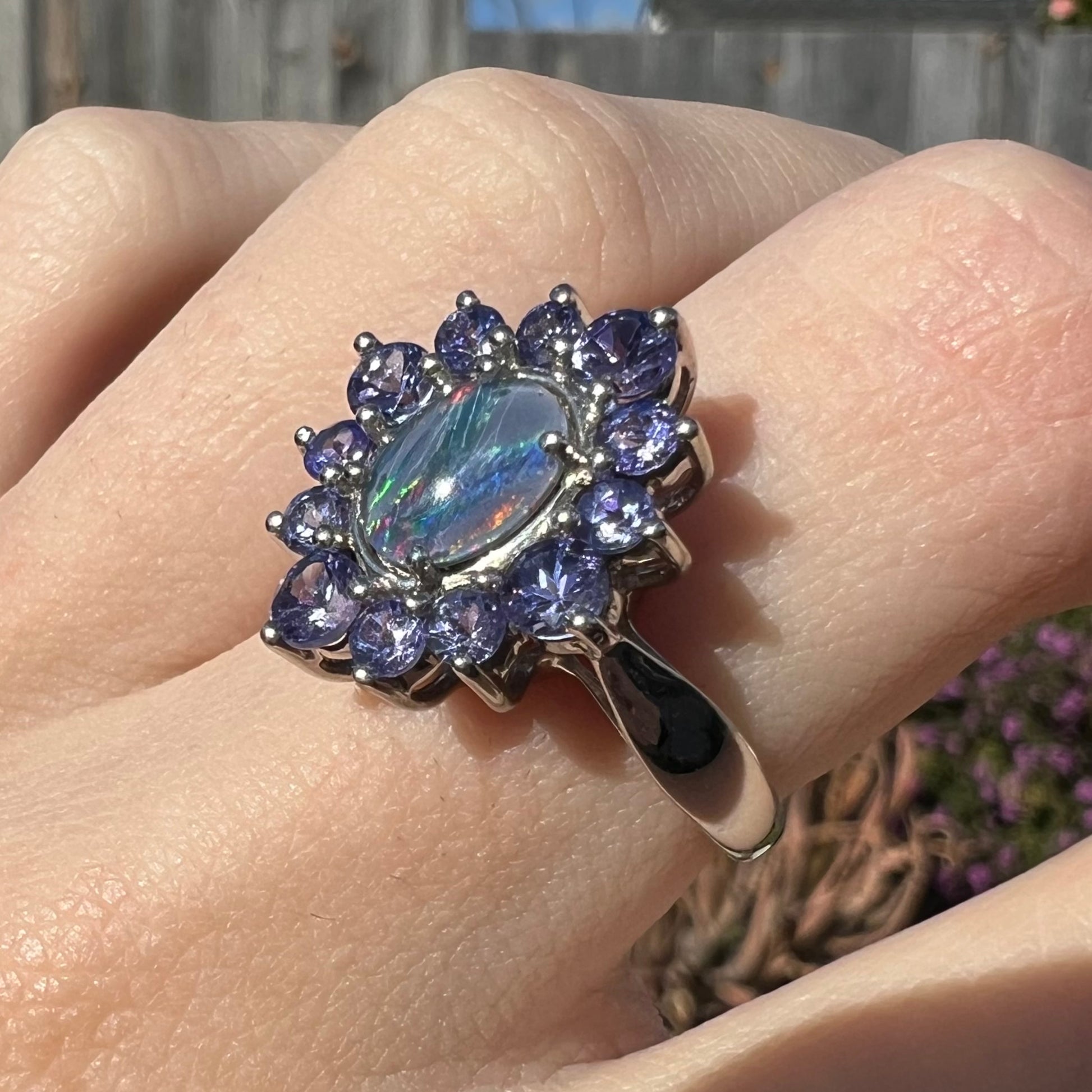 A sterling silver floating-style ring mounted with a black opal triplet in a halo of tanzanite stones.