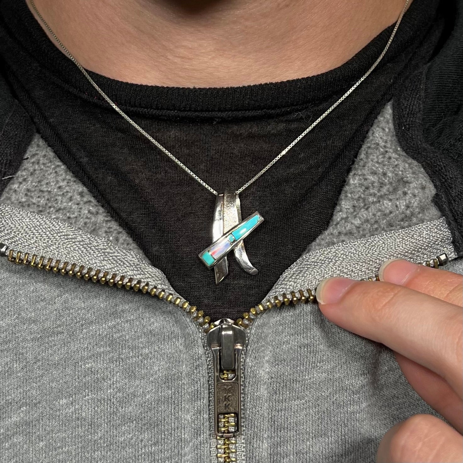 A folded design sterling silver turquoise and lab-created opal inlay necklace worn around a neck.