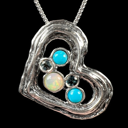 A sterling silver heart necklace set with Ethiopian opal, turquoise, and blue topaz, shown on black background.