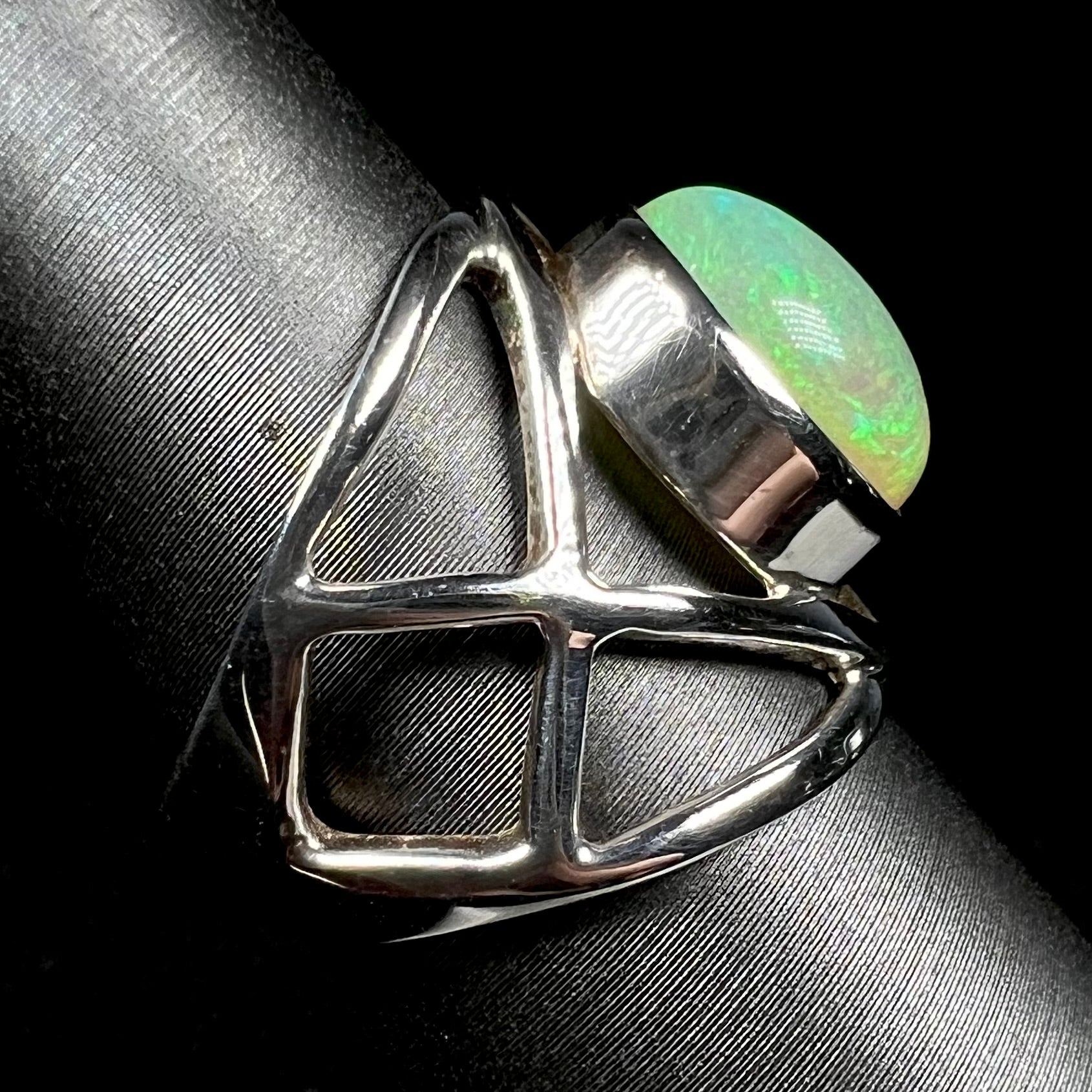 Side view of a silver open design ring against black background.