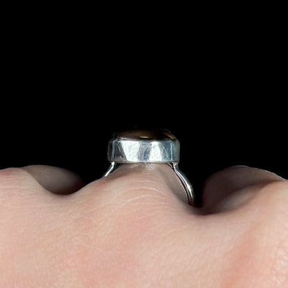 Side profile gallery view of a silver ring worn on a hand.