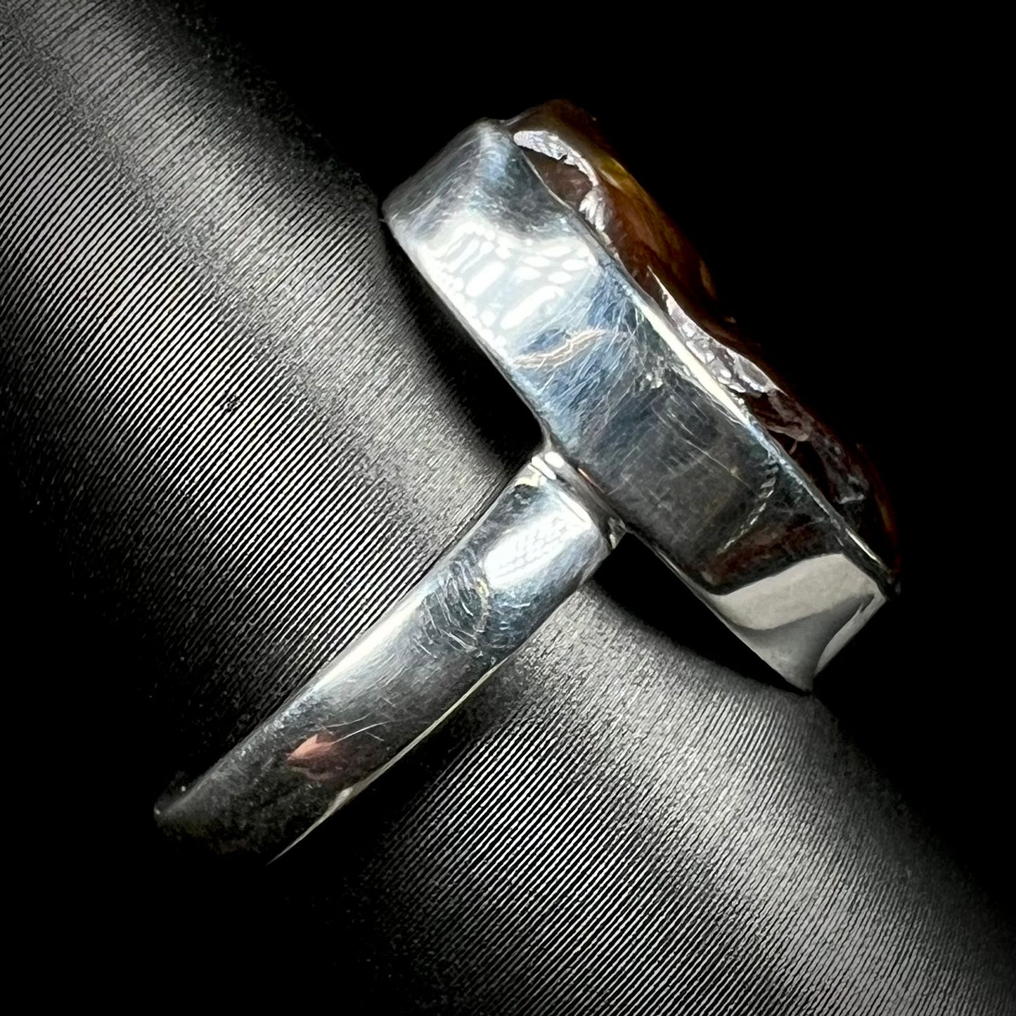 A handmade sterling silver ring set with a fire agate shown from the side view.