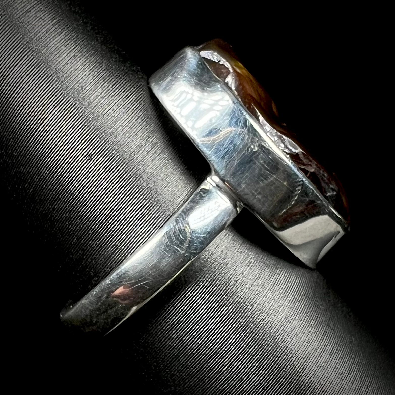 A handmade sterling silver ring set with a fire agate shown from the side view.