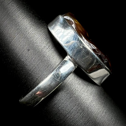 A handmade sterling silver ring set with a fire agate shown from the side view.