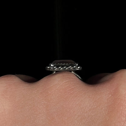 Side gallery view of the silver rope bezel on a fire agate ring, worn on a hand against a dark background.