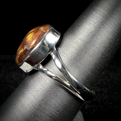 Side view of silver split shank fire agate ring against dark background.