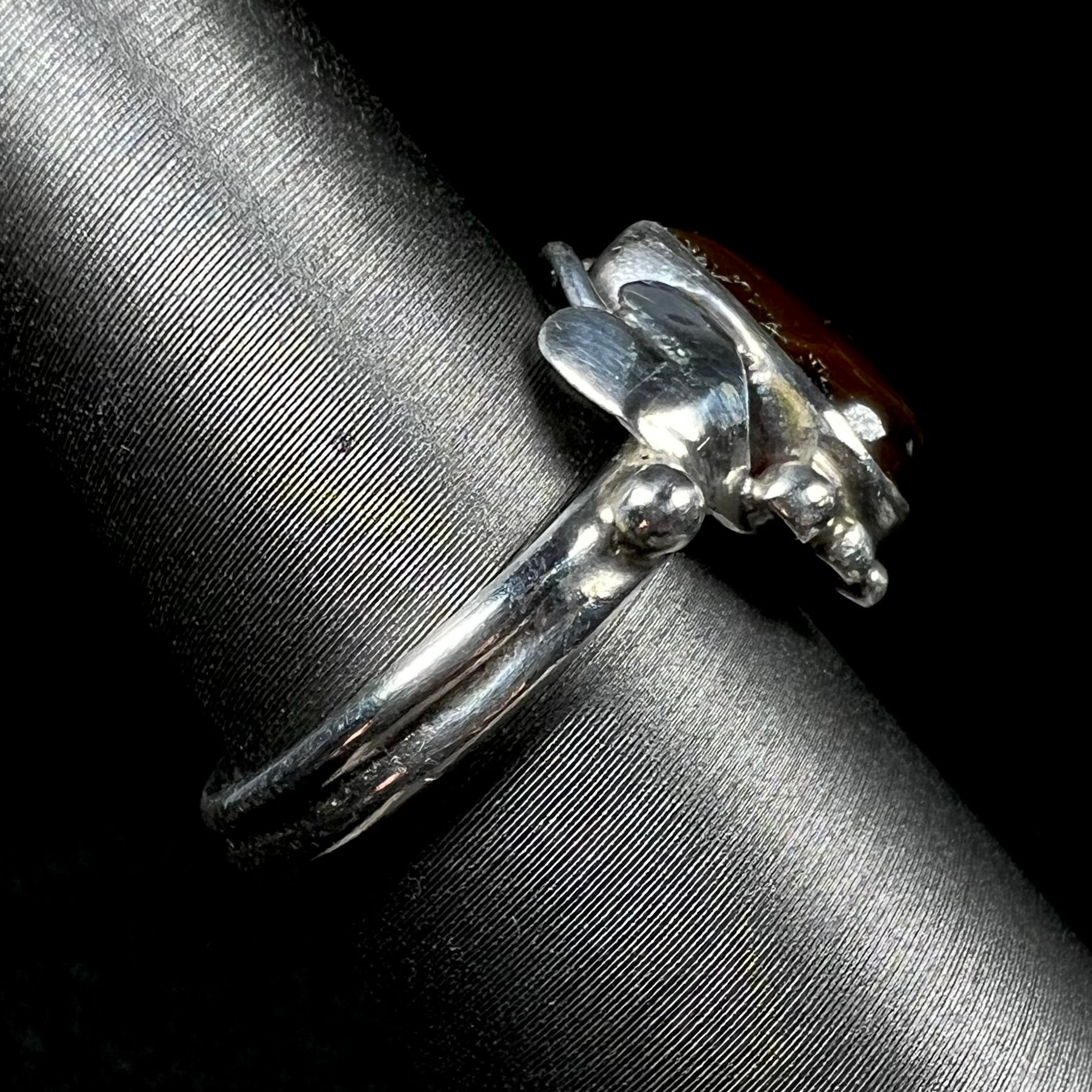 Side view of a silver fire agate ladies' ring with a leaf design showing.