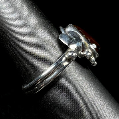 Side view of a silver fire agate ladies' ring with a leaf design showing.