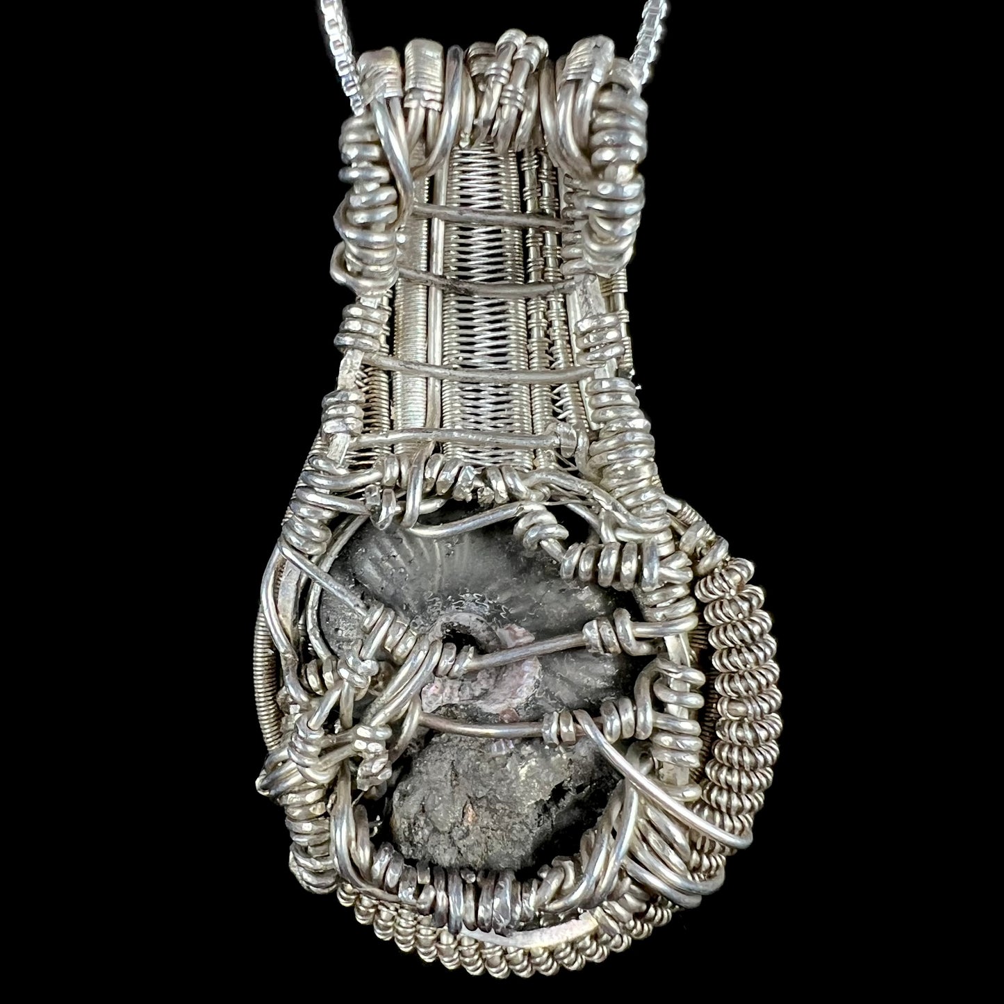 Back side of men's silver wire wrapped pendant set with ammonite fossil.