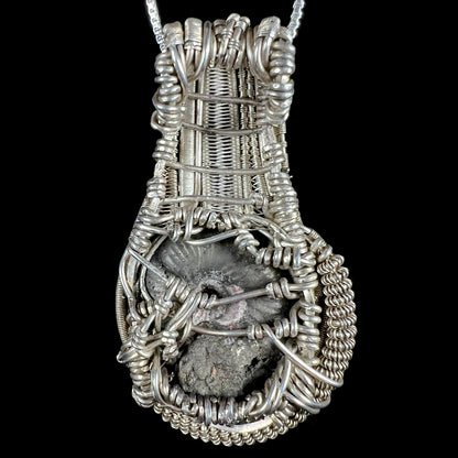 Back side of men's silver wire wrapped pendant set with ammonite fossil.