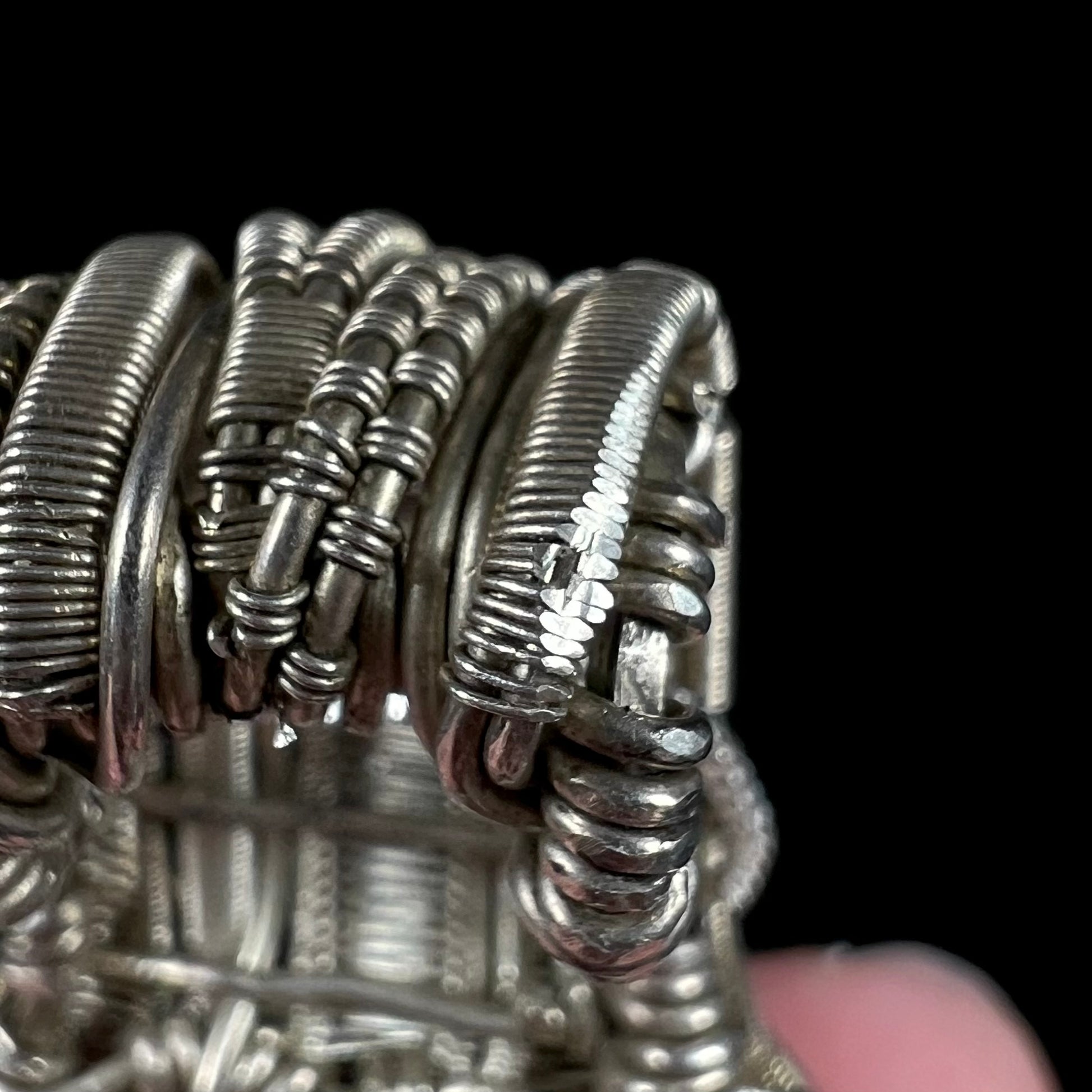 Close-up of the bail of a silver wire wrap pendant showing where the fine wire in the design was filed flat for metal testing purposes.