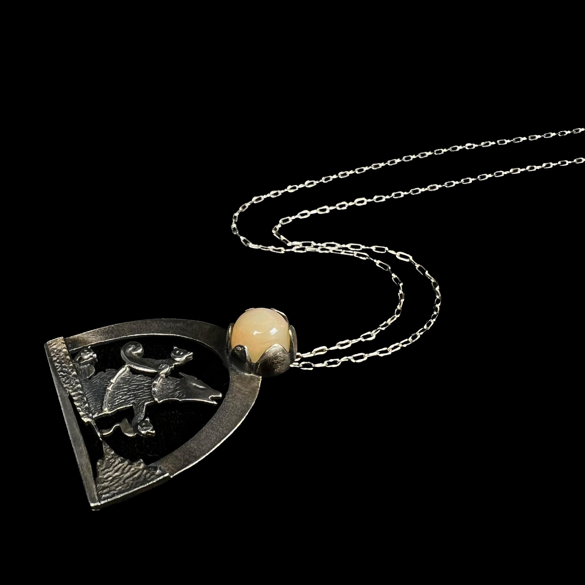 Angled editorial style view of a sterling silver Ethiopian opal wolf and cat design necklace.