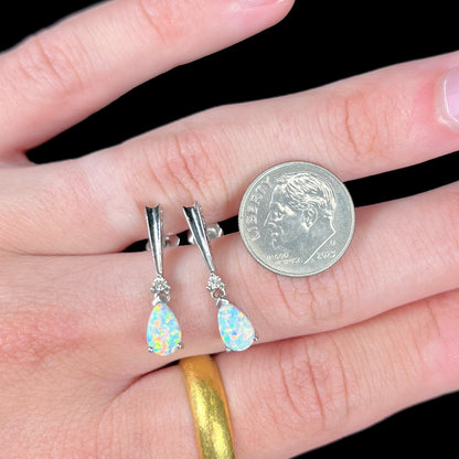 A pair of sterling silver filigree dangle earrings mounted with pear shaped lab created opals and diamond accents.