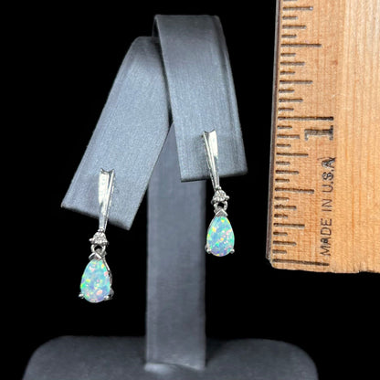 A pair of sterling silver filigree dangle earrings mounted with pear shaped lab created opals and diamond accents.