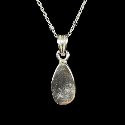 A natural, pear shaped Australian boulder opal with blue, purple, and green colors bezel set into a sterling silver necklace.