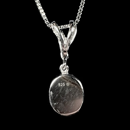 A sterling silver necklace set with a natural black opal doublet and white zircon accent stones.